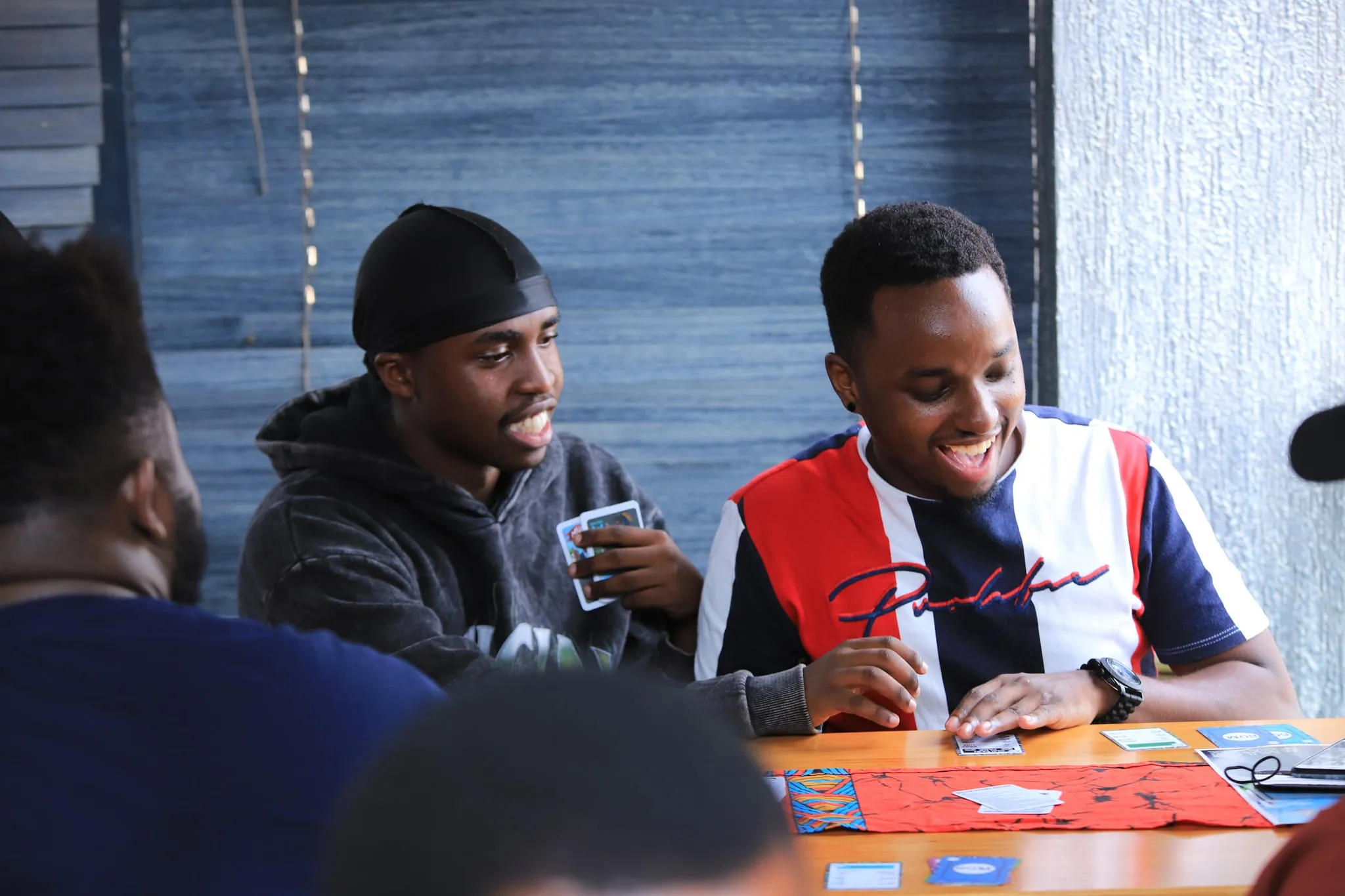 Two young men grinning across the table mid-game