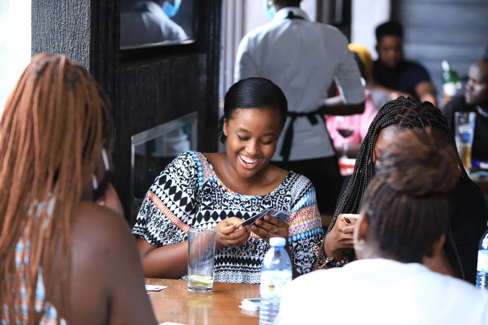 A player smiling down at her Mulodi hand at a busy table