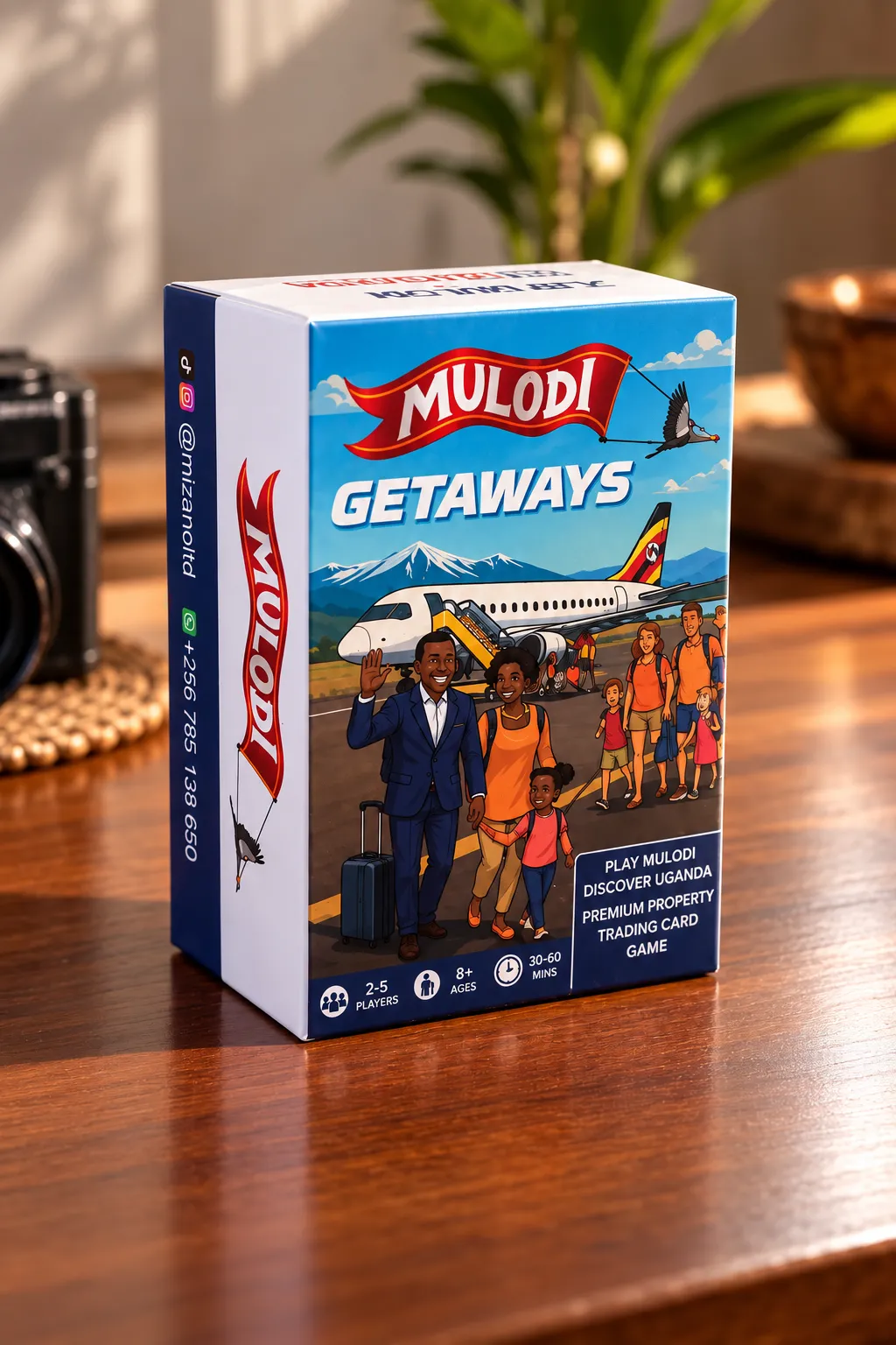 Mulodi Getaways box on a wooden table, showing a family waving beside a plane with Ugandan colours